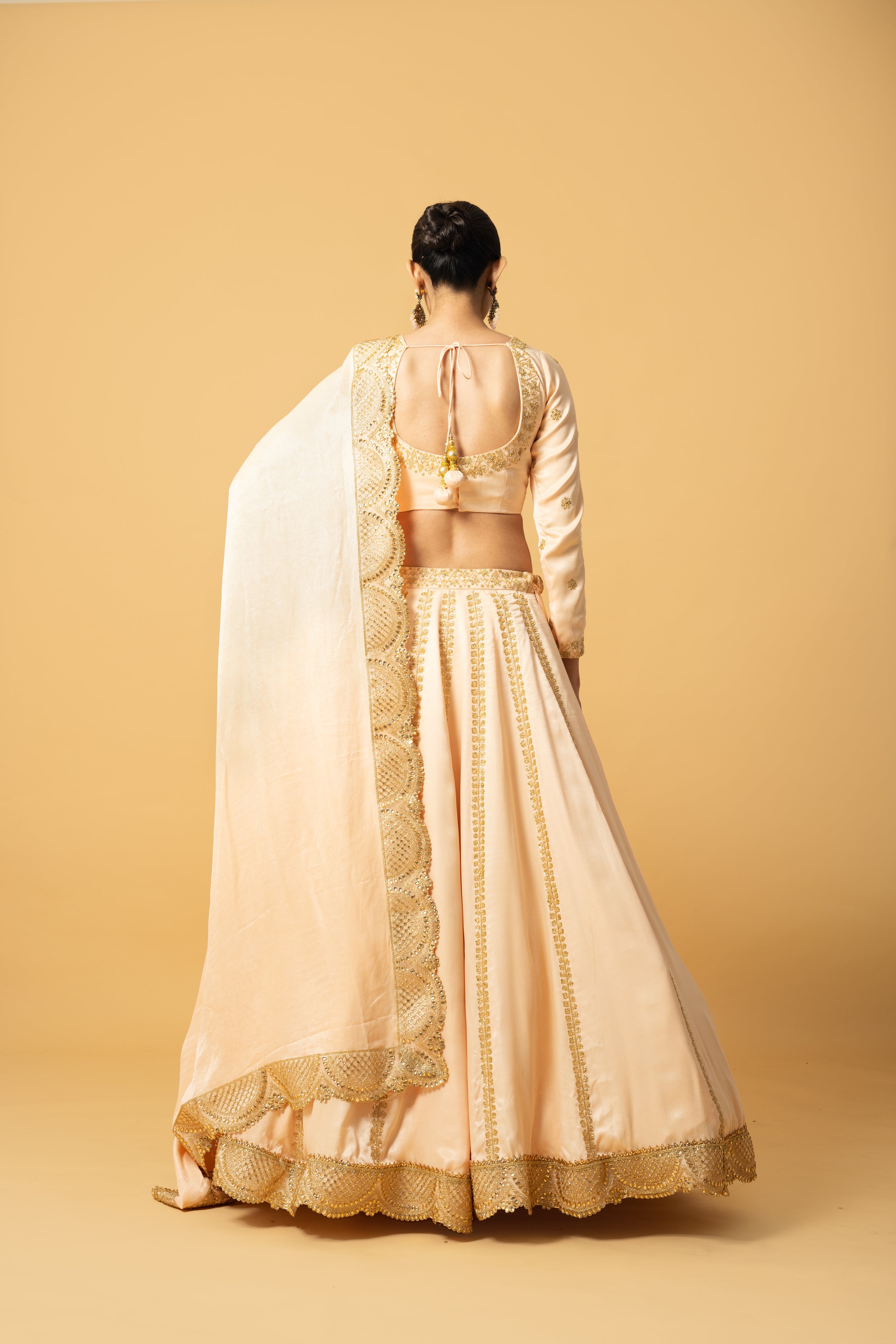 Peach modal satin lehenga with full sleeves, hand embroidery, and lace-trimmed dupatta.